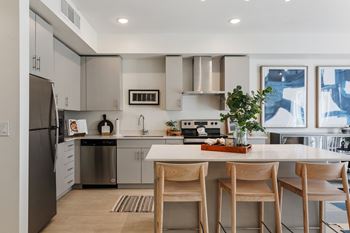 A modern kitchen with a refrigerator, stove, and sink.